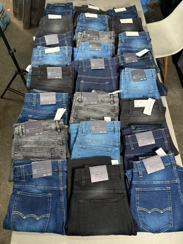 Veinticuatro pantalones de mezclilla doblados en tres columnas, surtidos en azul, negro y gris