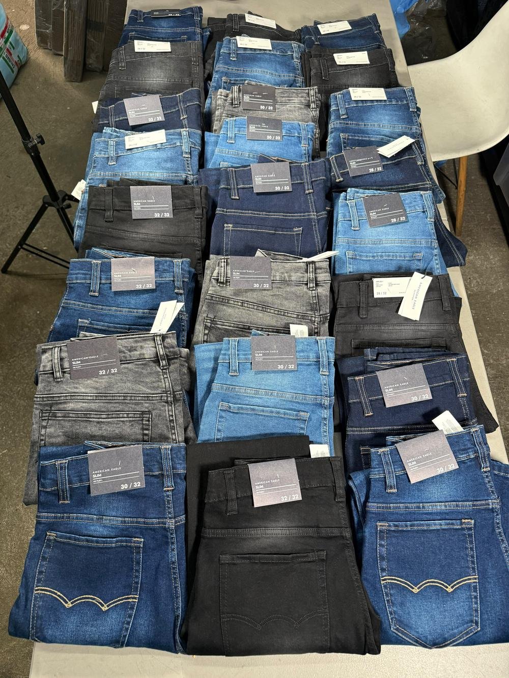 Veinticuatro pantalones de mezclilla doblados en tres columnas, surtidos en azul, negro y gris