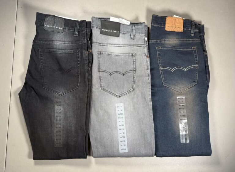Tres pantalones de mezclilla doblados en tono negro, gris y azul