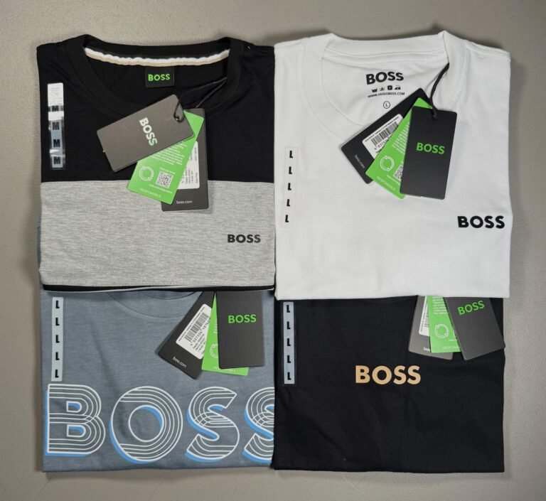 Playeras de cuello redondo dobladas en negro, blanco, gris y azul con etiqueta