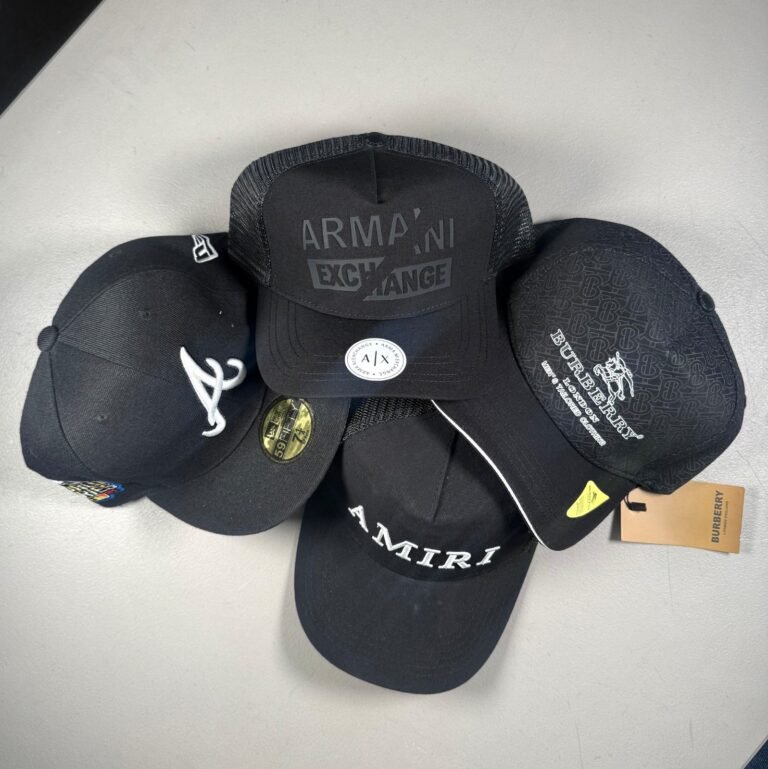 Gorras negras de distintas marcas apiladas sobre una superficie clara