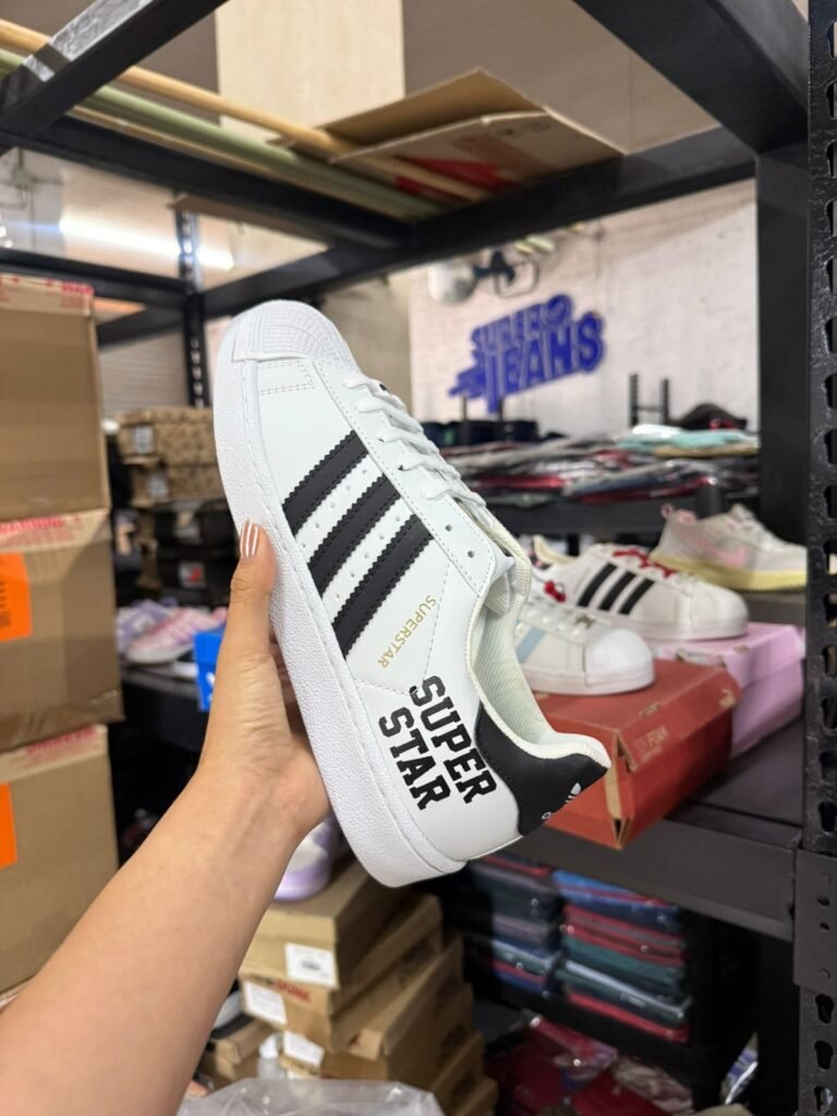 Mano sosteniendo un tenis deportivo blanco dentro de la tienda