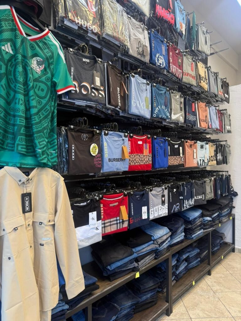 Estantes con ropa colgada y playeras en la tienda de mayoreo