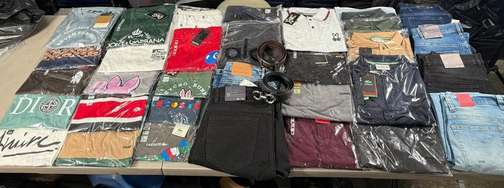 Prendas surtidas de la SuperPaca Mega sobre dos mesas: playeras de cuello redondo, playeras tipo polo, jeans, shorts y cintos