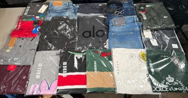 Prendas surtidas de la SuperPaca Mix sobre la mesa: playeras de cuello redondo, playeras tipo polo, dos jeans y un cinto