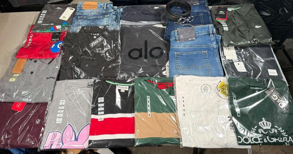Prendas surtidas de la SuperPaca Mix sobre la mesa: playeras de cuello redondo, playeras tipo polo, dos jeans y un cinto